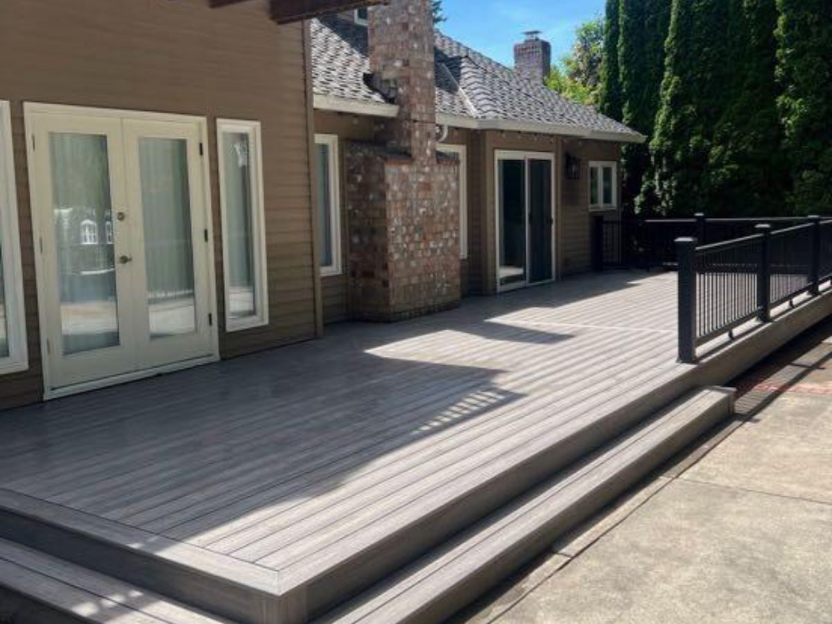 Composite deck with wraparound steps and black metal railing by Ready Set Remodel